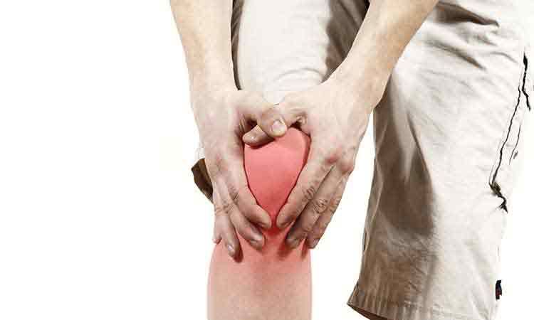Person holding painful, red, inflamed knee.