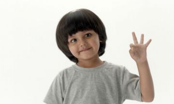 Smiling child showing three fingers.