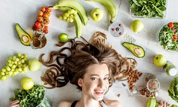Woman surrounded by healthy food and fitness items.